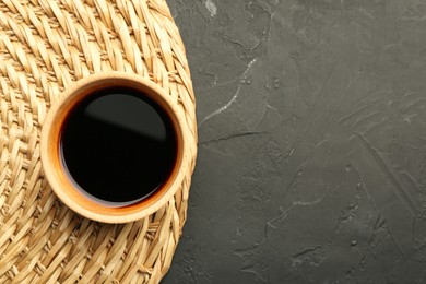 Soy sauce in bowl on black textured table, top view. Space for text