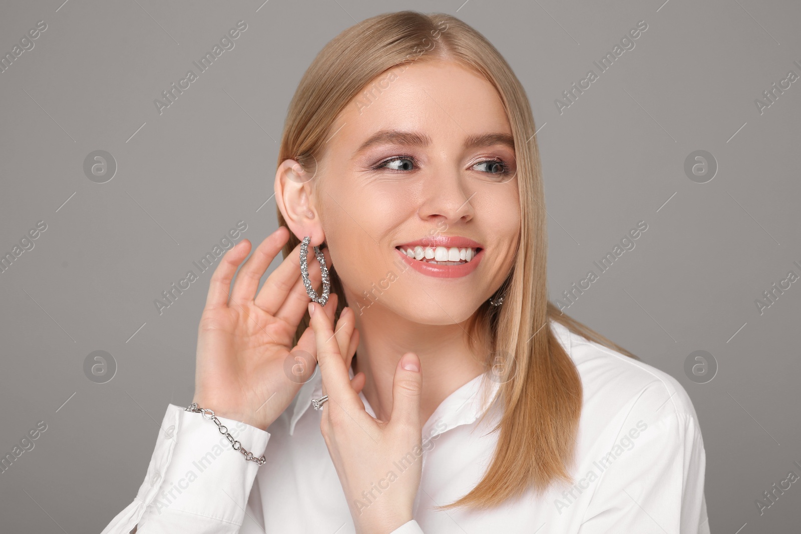 Photo of Beautiful young woman with elegant jewelry on gray background