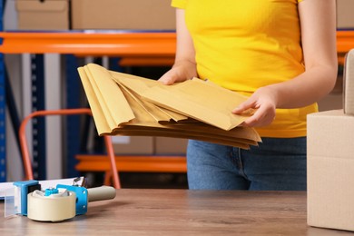 Photo of Post office worker with adhesive paper bags at counter indoors, closeup