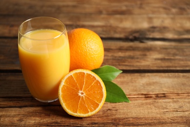 Photo of Glass of orange juice and fresh fruits on wooden table. Space for text