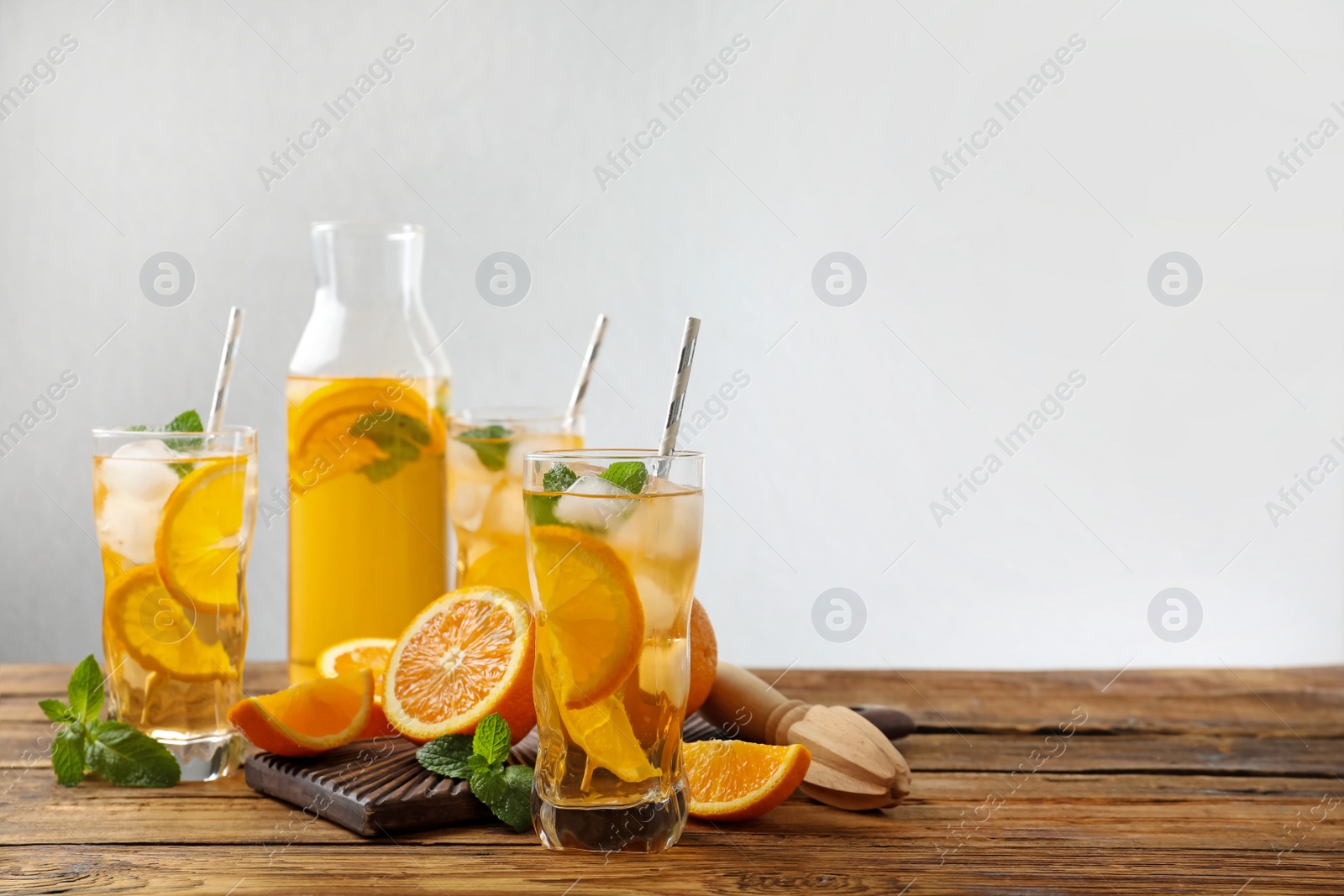 Photo of Delicious refreshing drink with orange slices on wooden table. Space for text