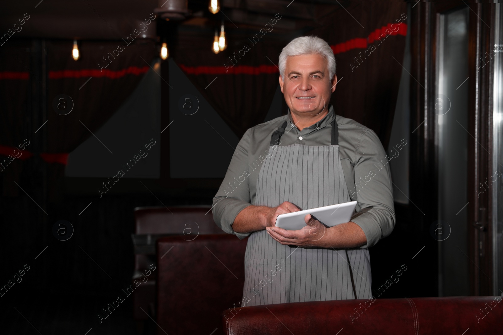 Photo of Senior business owner with tablet in his restaurant