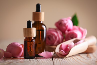 Bottles of essential oil and roses on white wooden table against beige background