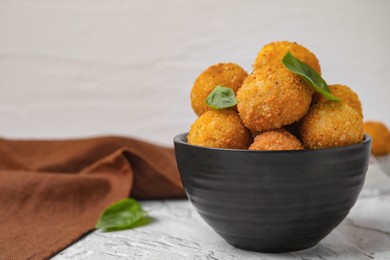 Bowl of delicious fried tofu balls with basil on textured table, space for text