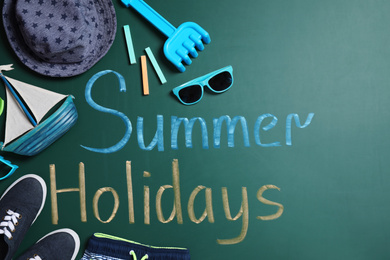 Different child accessories and text Summer Holidays on green chalkboard, flat lay. School's Out