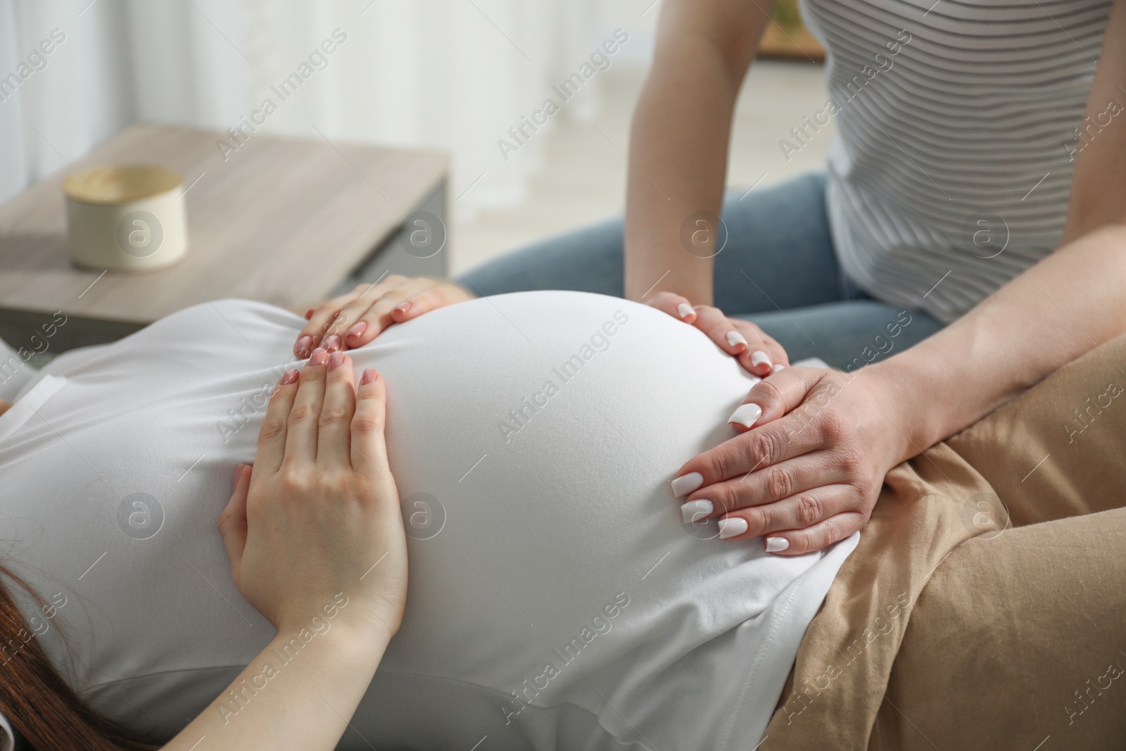 Photo of Doula taking care of pregnant woman indoors, closeup. Preparation for child birth