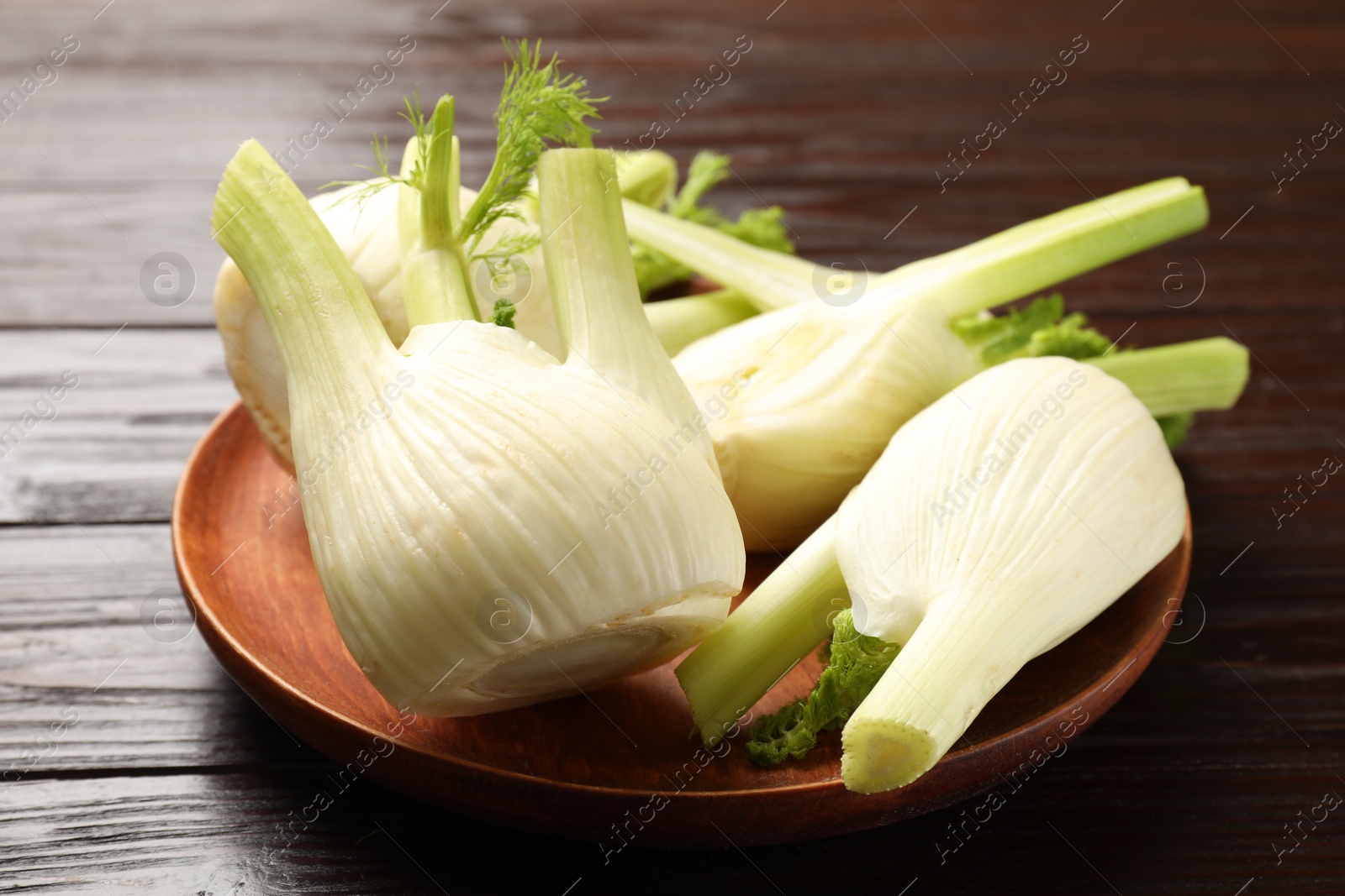 Photo of Fresh raw fennel bulbs on wooden table, closeup