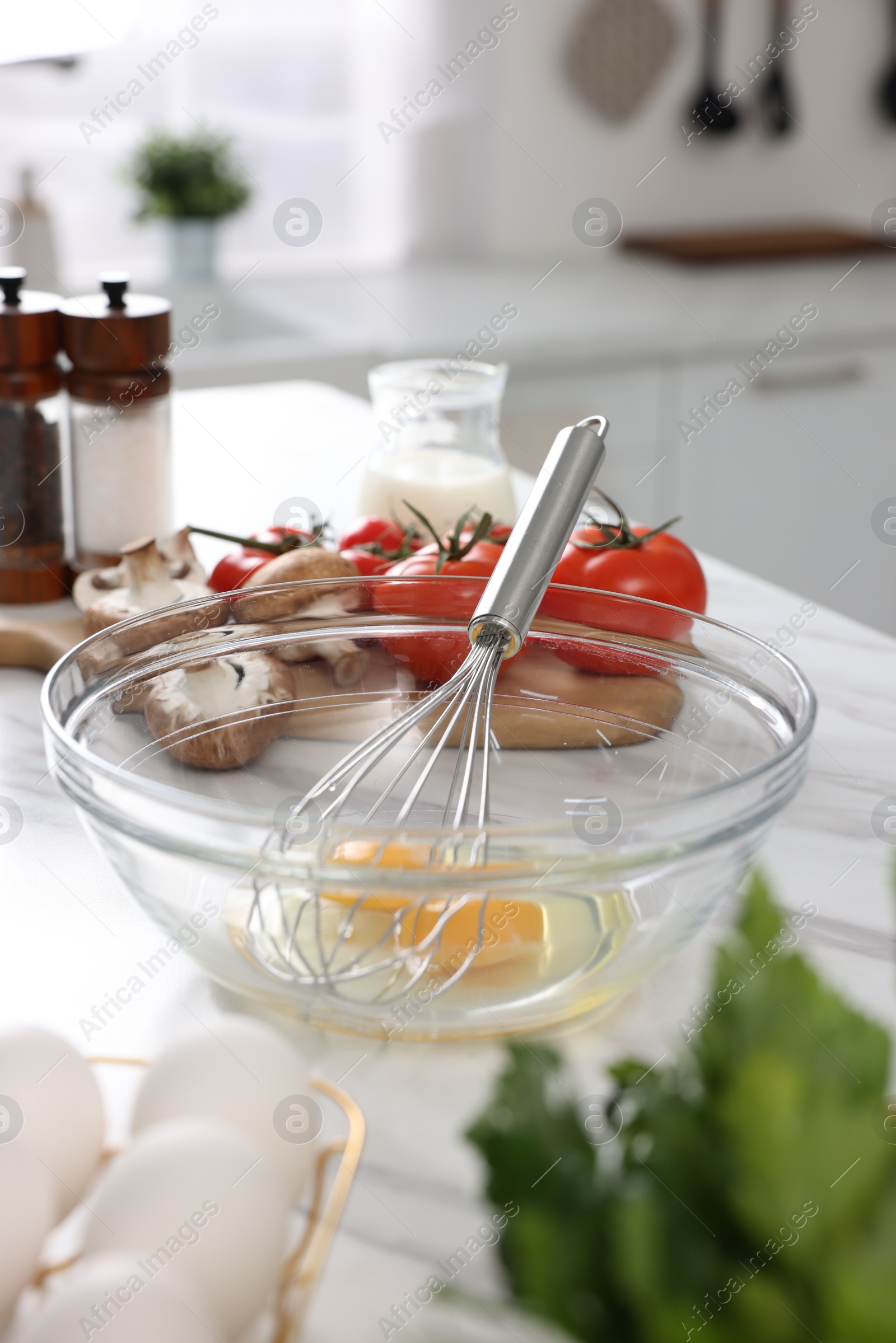 Photo of Whisk, bowl, and different ingredients on white marble table indoors