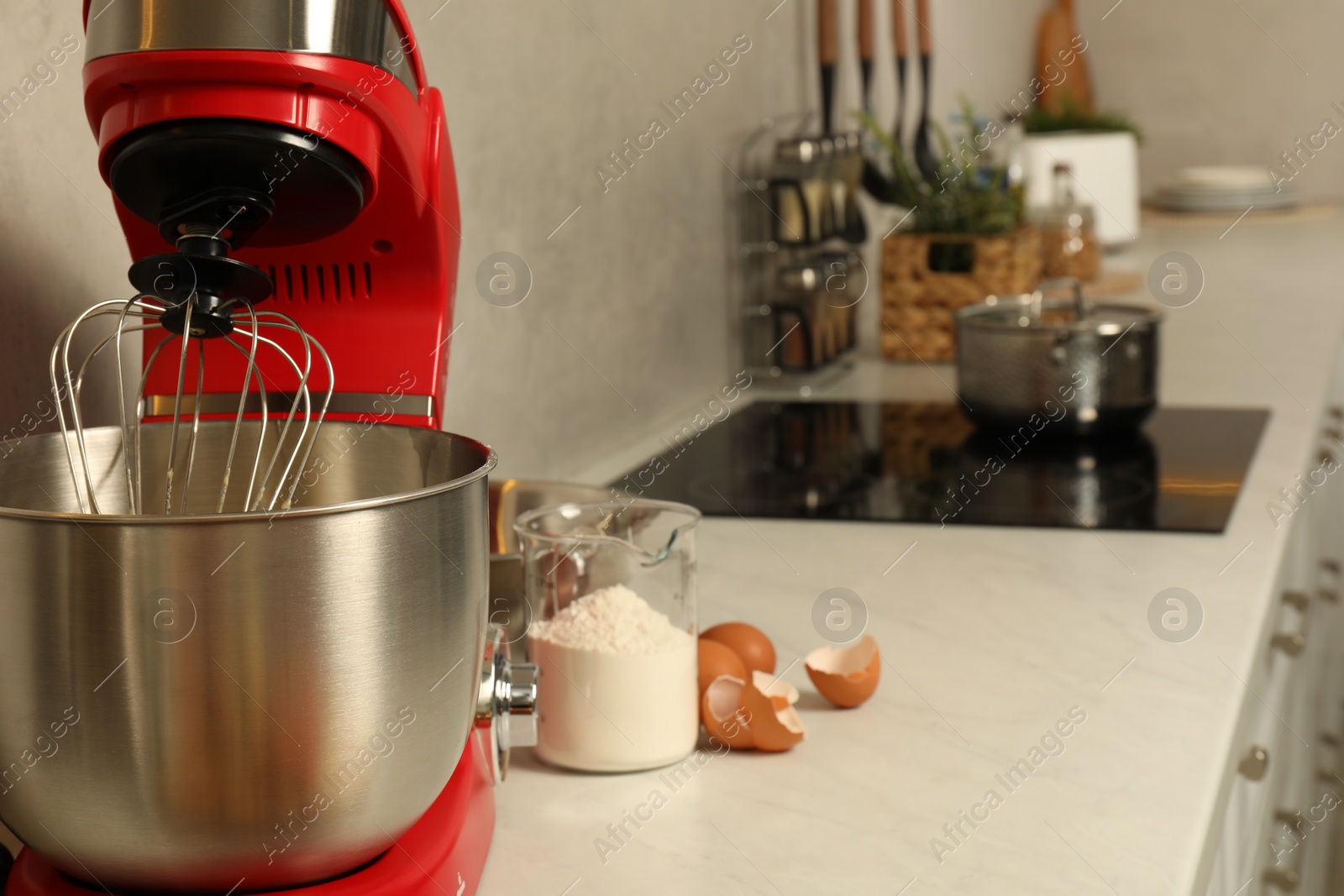 Photo of Modern red stand mixer, eggs and container with flour on white marble countertop in kitchen. Space for text