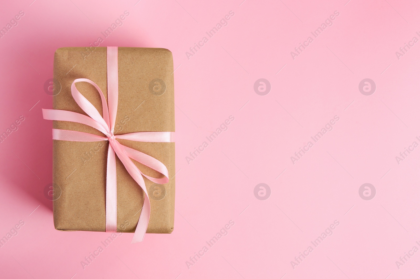 Photo of Beautiful gift box with bow on pink background, top view. Space for text