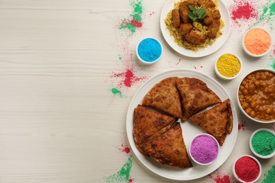 Photo of Traditional Indian food and color powders on white wooden table, flat lay with space for text. Holi festival celebration
