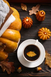 Photo of Cup of hot drink and pumpkin shaped candles on wooden table, flat lay. Cozy autumn atmosphere