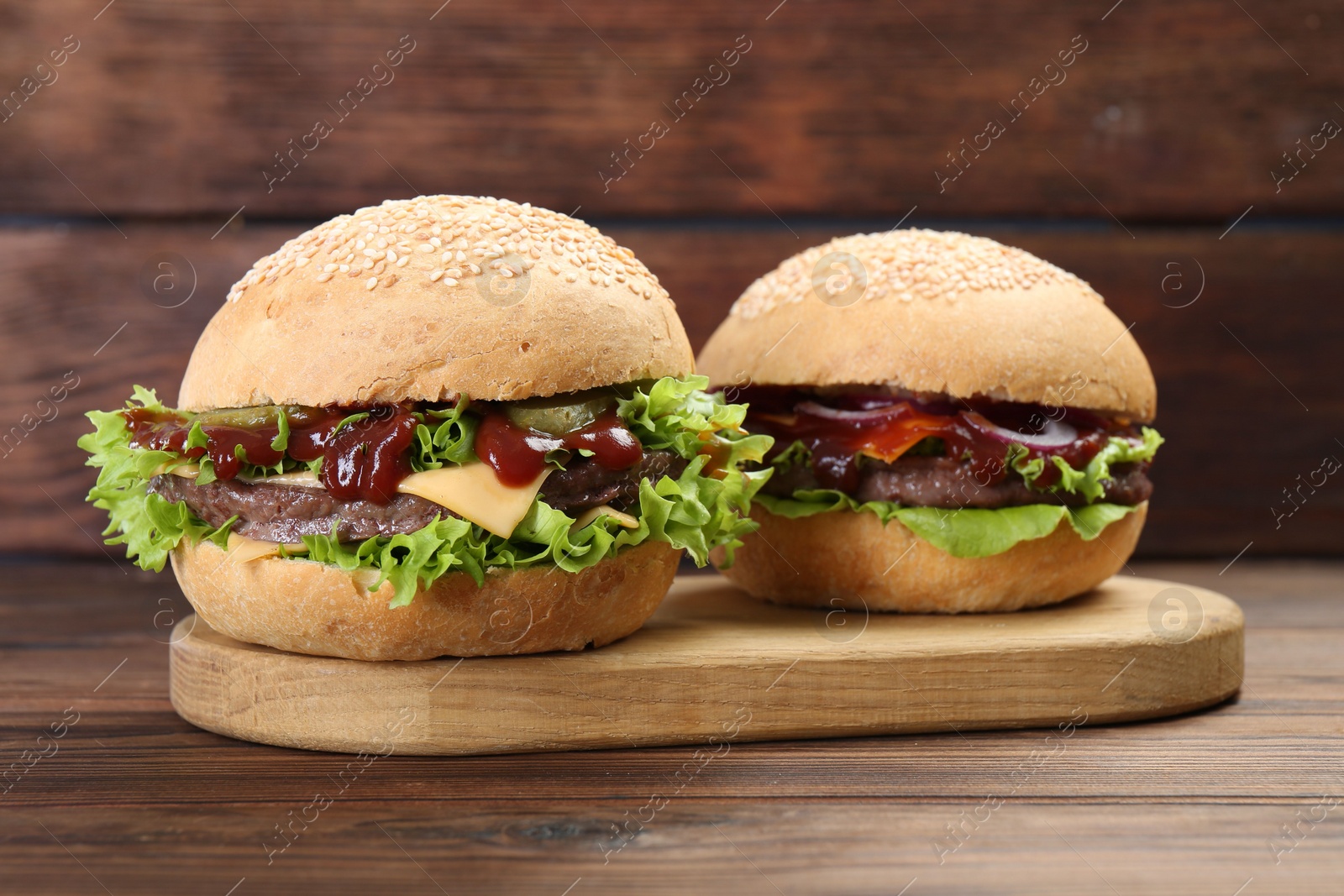 Photo of Board with delicious cheeseburgers on wooden table, closeup