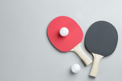 Photo of Ping pong rackets and balls on grey background, flat lay. Space for text