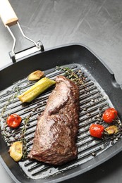 Photo of Delicious grilled beef meat and vegetables in pan on grey table, closeup