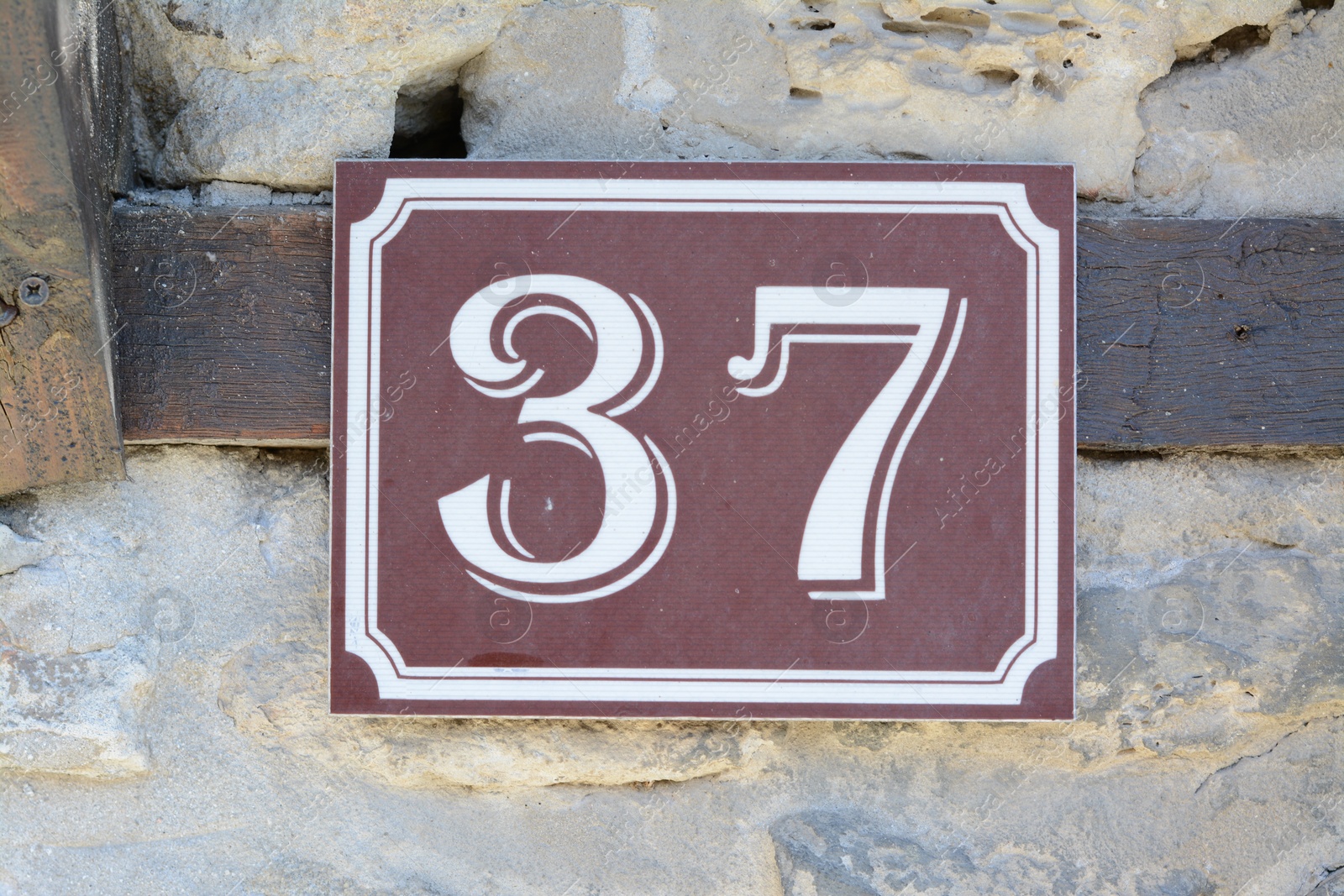 Photo of Plate with house number thirty seven on stone wall outdoors, closeup