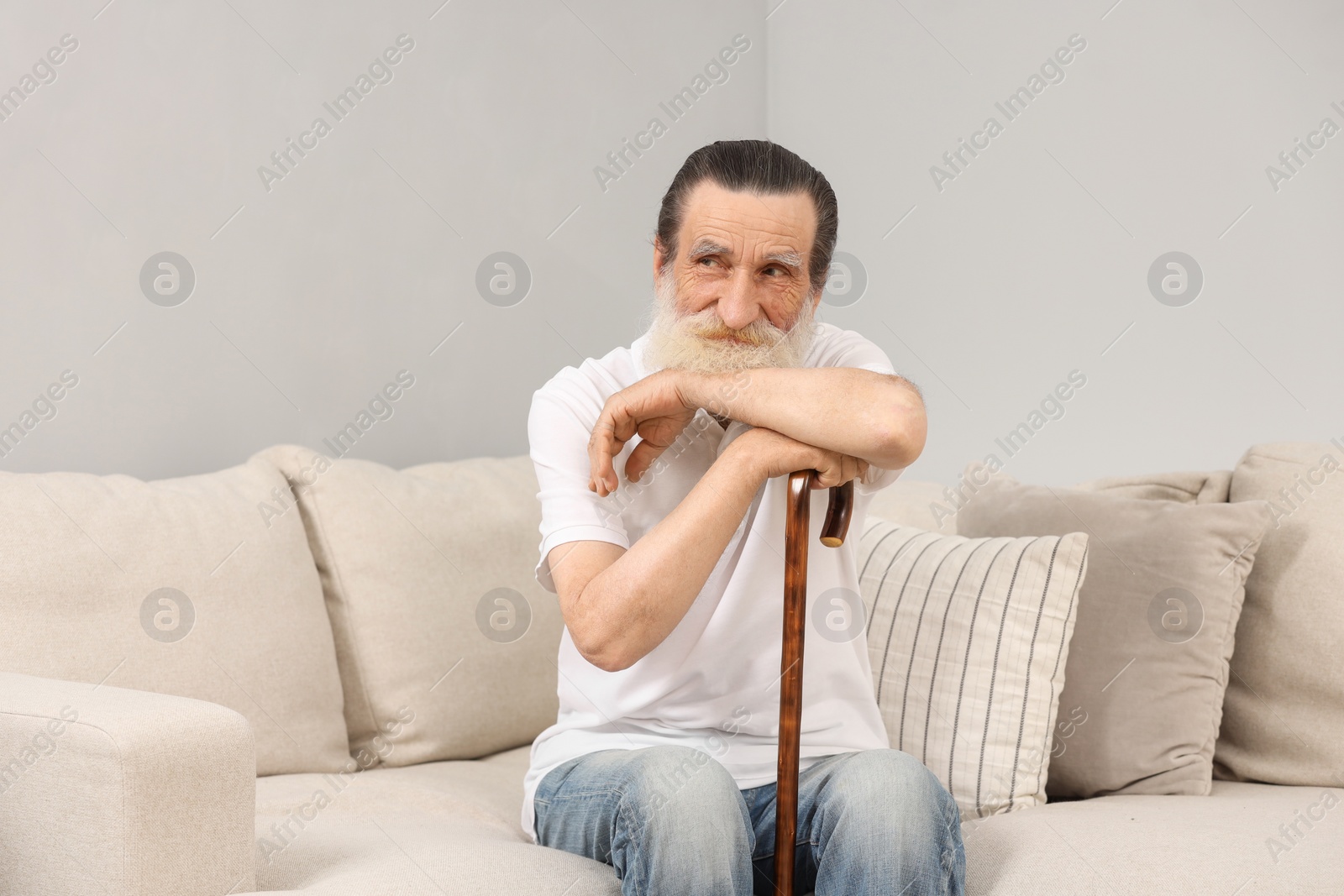 Photo of Senior man with walking cane on sofa indoors
