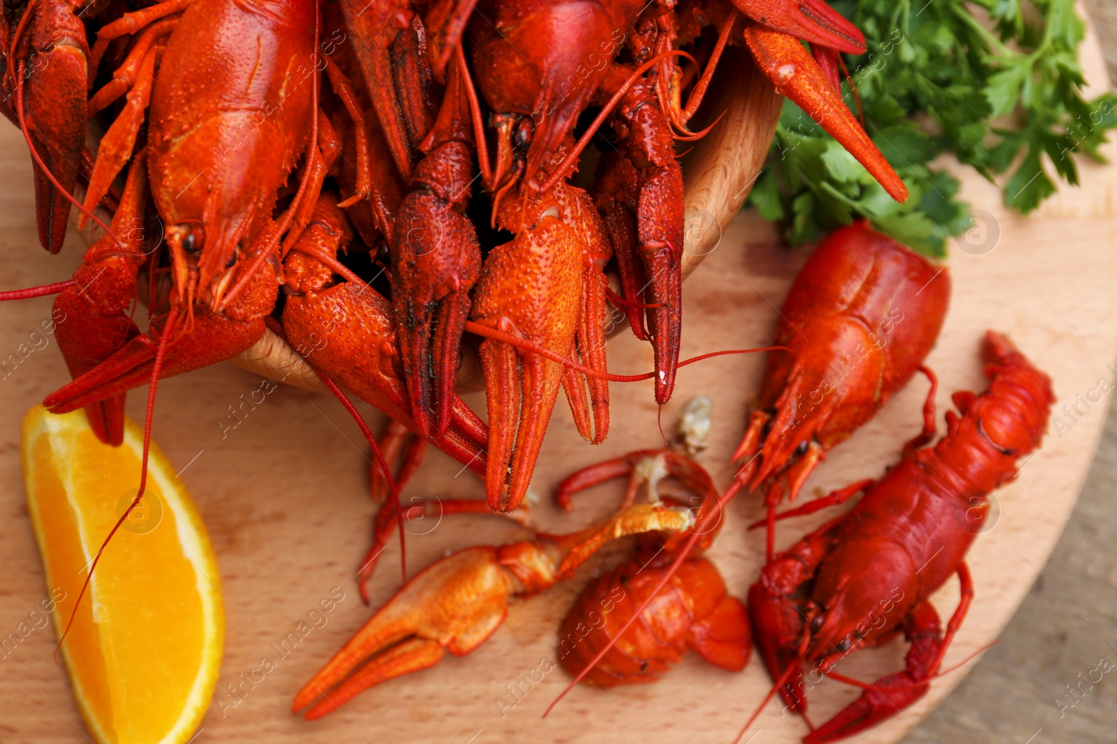 Photo of Delicious red boiled crayfish and orange on wooden table, top view