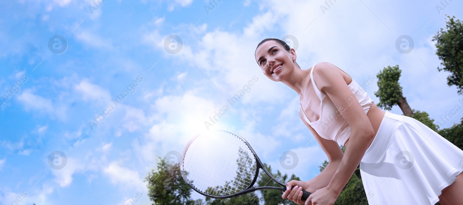 Image of Young woman playing tennis outdoors, low angle view. Banner design with space for text