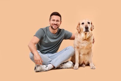 Man hugging with adorable Labrador Retriever dog on beige background. Lovely pet