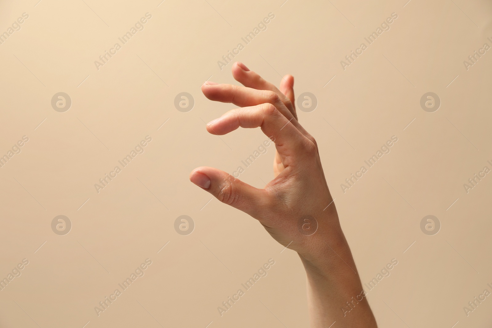 Photo of Woman holding something in hand on beige background, closeup