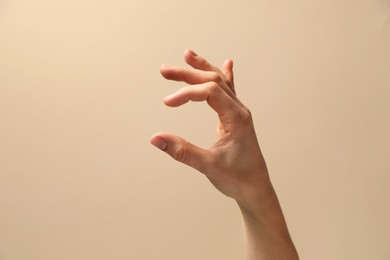 Woman holding something in hand on beige background, closeup