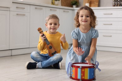 Photo of Little children playing toy musical instruments in kitchen