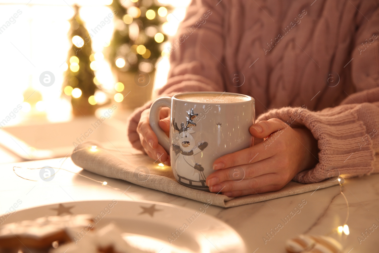Photo of Woman holding cup with hot drink indoors, closeup