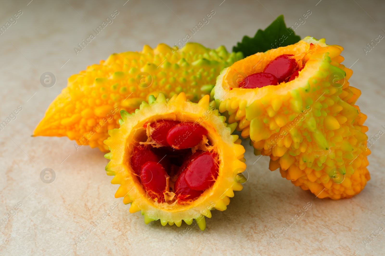 Photo of Fresh bitter melons with red seeds on light table, closeup