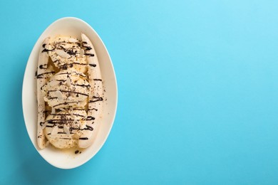 Delicious banana split ice cream with toppings on light blue background, top view. Space for text