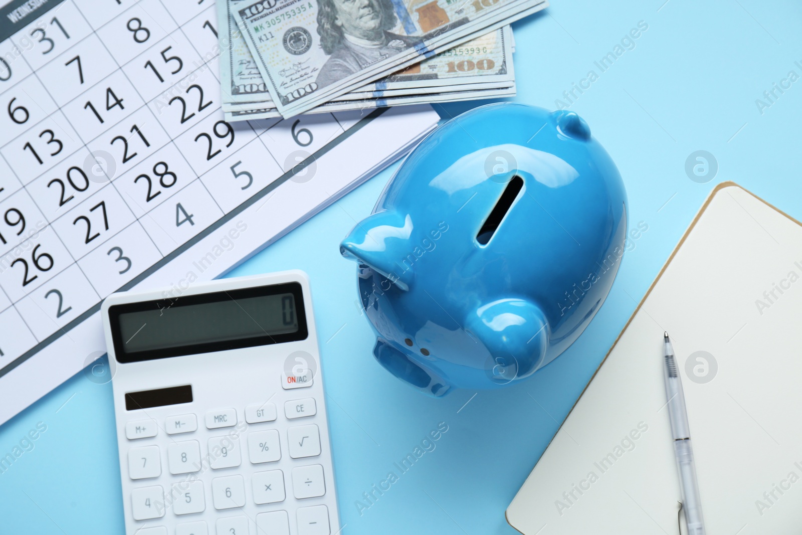 Photo of Flat lay composition with piggy bank and calculator on light blue background
