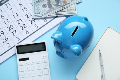 Flat lay composition with piggy bank and calculator on light blue background