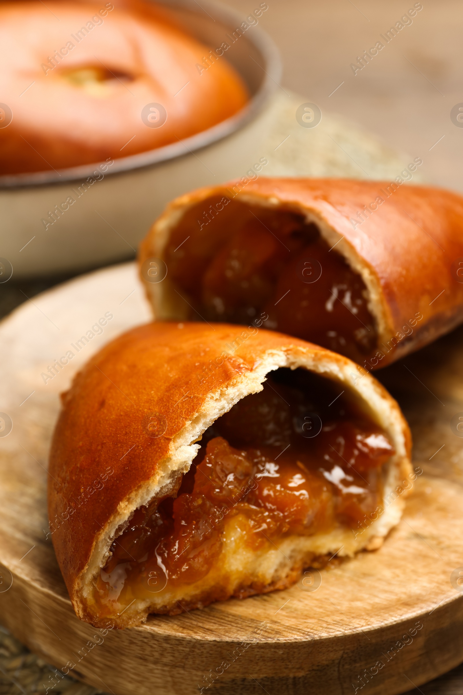 Photo of Delicious baked patties with jam on wooden board, closeup