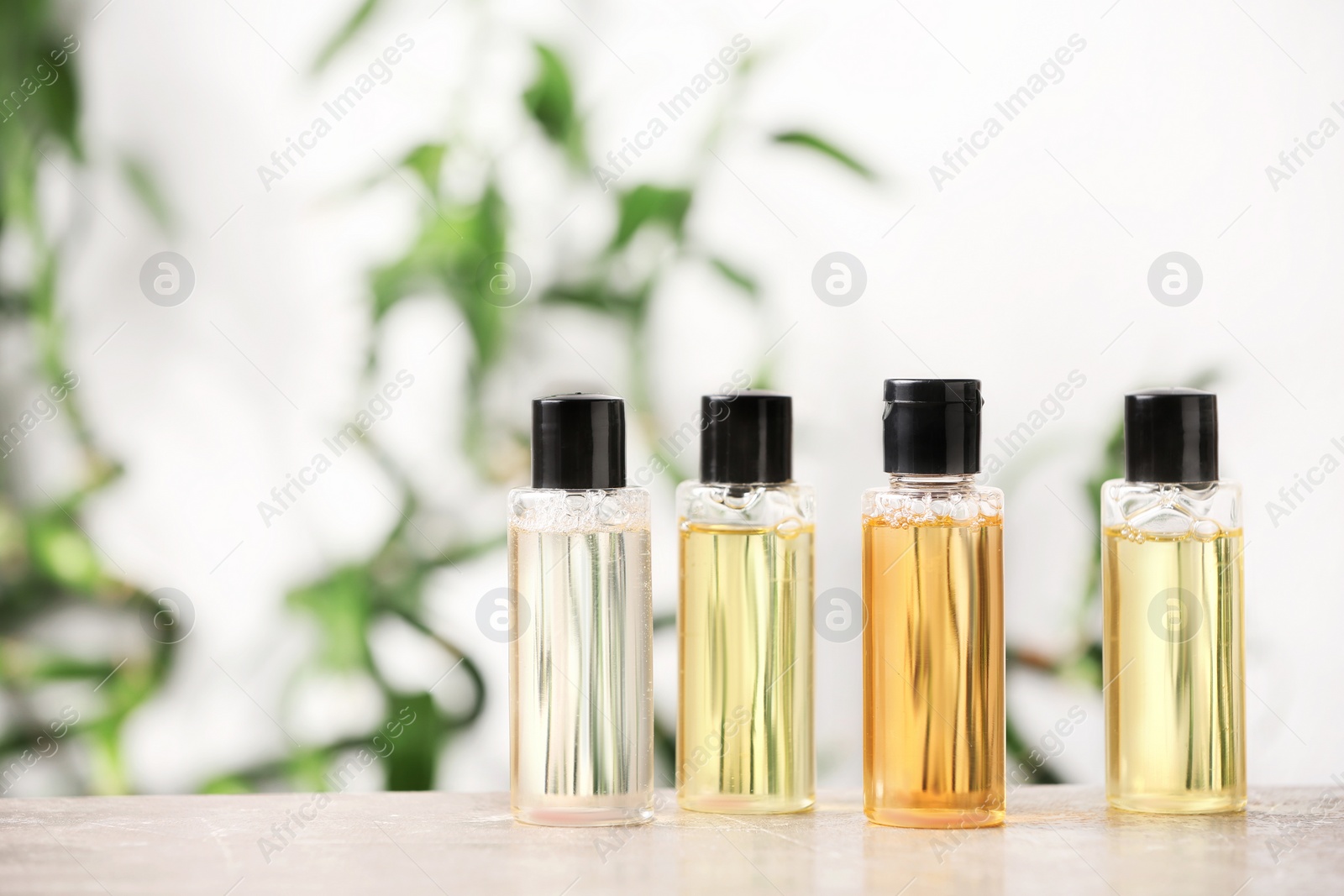 Photo of Mini bottles with cosmetic products on table against blurred background. Hotel amenities