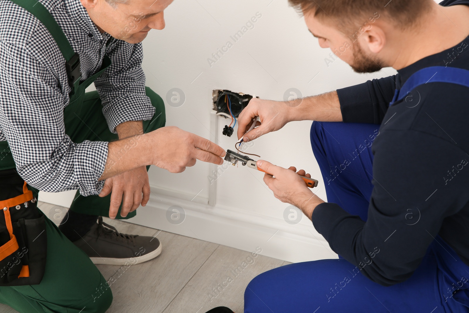 Photo of Electrician and apprentice working with wires indoors