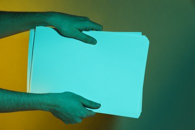 Photo of Man holding sheets of paper on dark background, closeup and space for text. Color tone effect