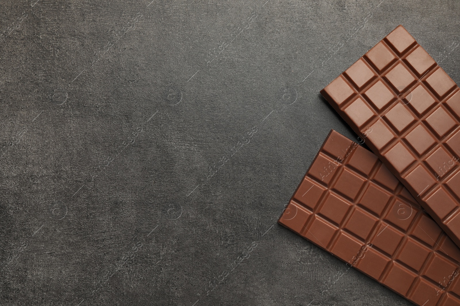 Photo of Delicious milk chocolate bars on black table, flat lay. Space for text