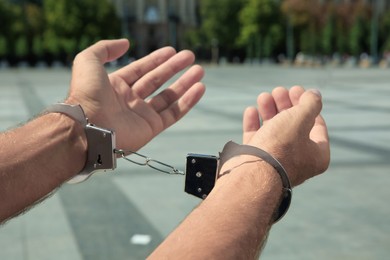 Man in handcuffs on city street, closeup