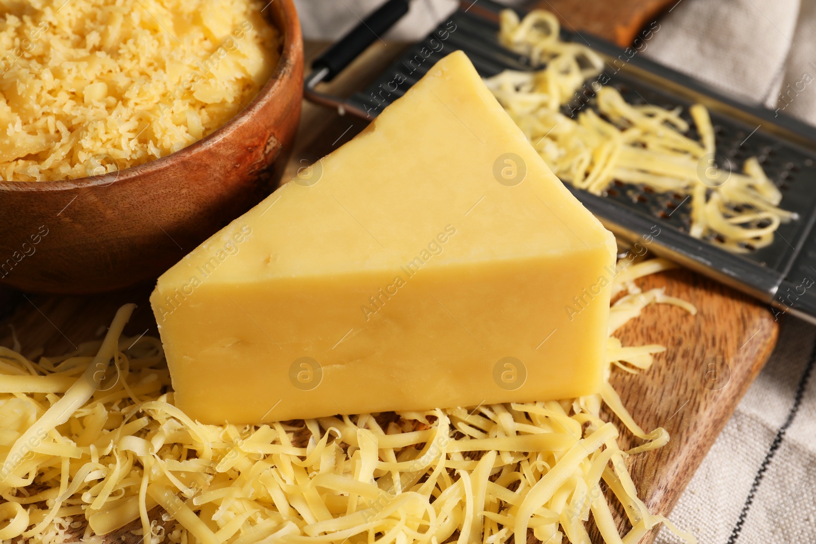 Photo of Grated and whole piece of cheese on table, closeup