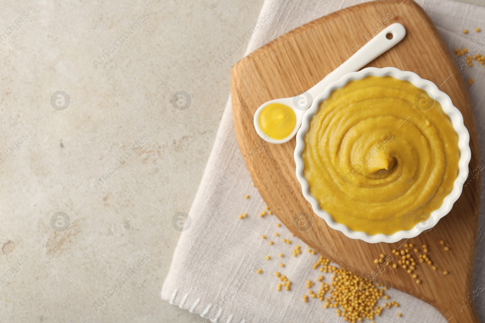 Photo of Tasty mustard sauce and dry seeds on light textured table, flat lay. Space for text