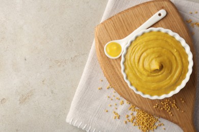 Photo of Tasty mustard sauce and dry seeds on light textured table, flat lay. Space for text