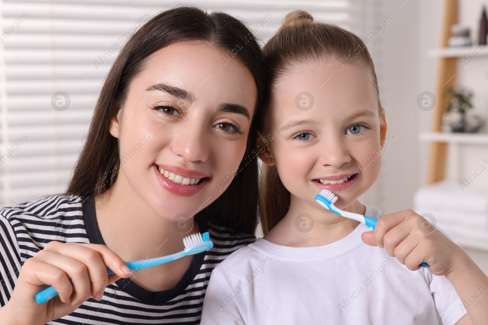 Photo of Mother and her daughter brushing teeth together in bathroom