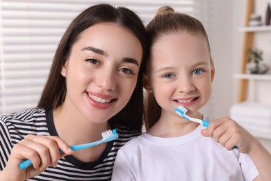 Mother and her daughter brushing teeth together in bathroom