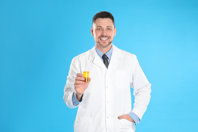 Photo of Professional pharmacist with pills on light blue background