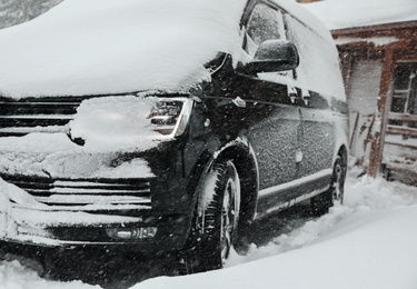 Modern car covered with snow outdoors on winter day, closeup