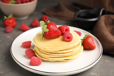 Tasty pancakes with fresh berries on grey table