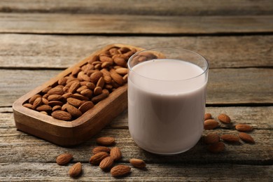 Photo of Glass of almond milk and almonds on wooden table
