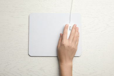 Photo of Woman using wired computer mouse on white wooden table, top view. Space for text