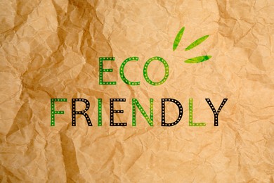 Phrase Eco Friendly written on crumpled kraft paper, top view