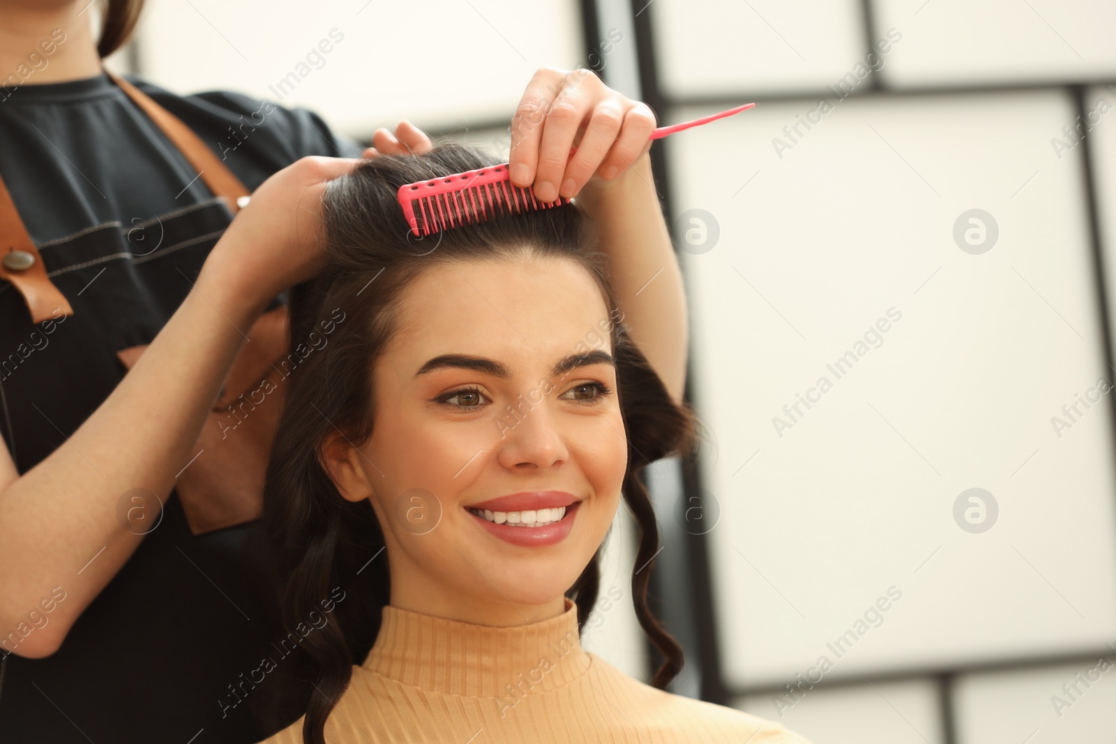 Photo of Professional hairdresser combing woman's hair indoors, closeup. Space for text